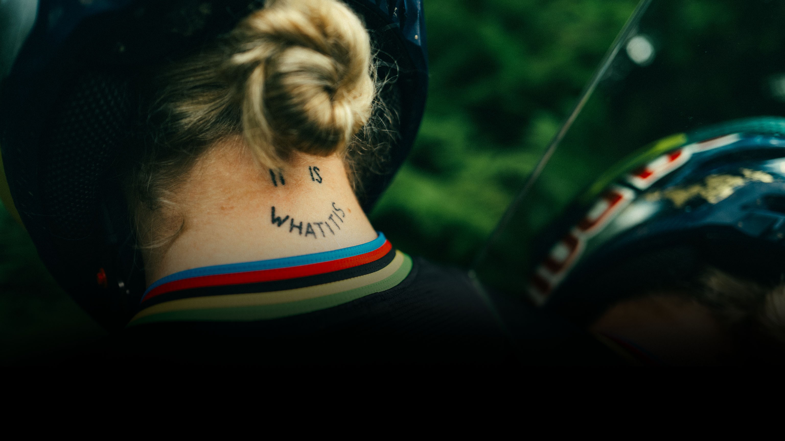 Close-up shot of Vali Höll’s neck tattoo and title of the athlete’s YouTube series, “It is what it is”.